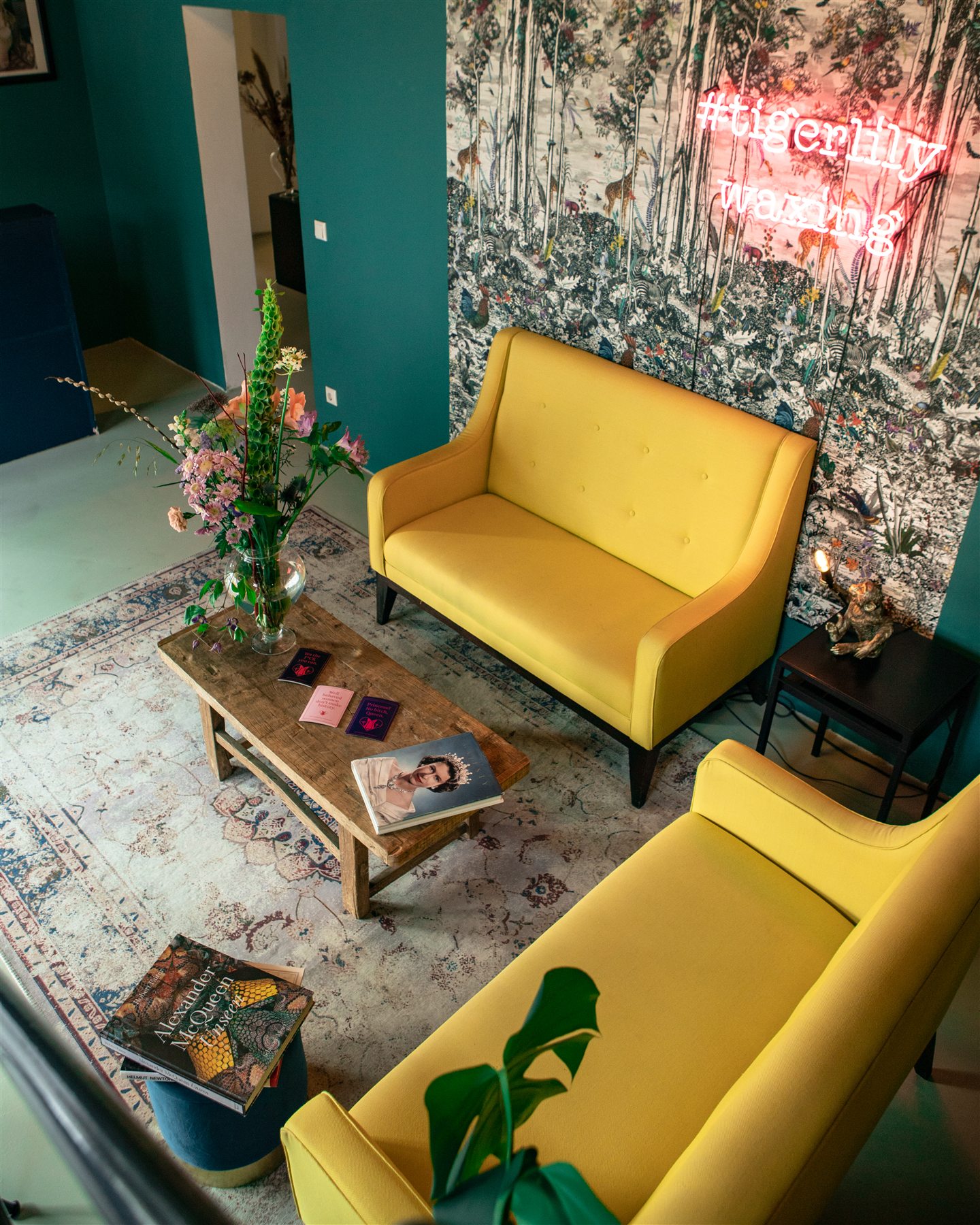 Farbenfroher Wartebereich im Tigerlily-Studio mit gelben Sesseln und Neon-Schriftzug